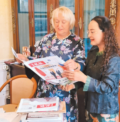 李雙杰(右)向俄羅斯友人展示《龍報》。